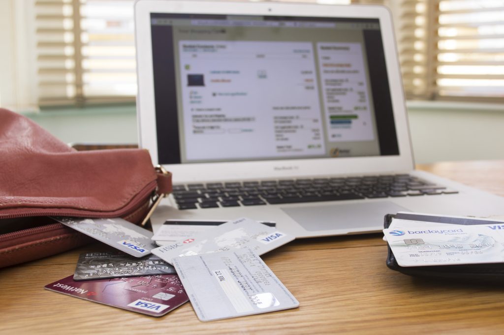 Credit cards scattered on desk in front of an open laptop - Unexplained Wealth Orders can lead to investigation of assets