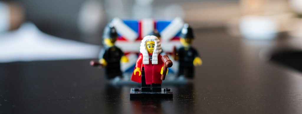 Close-up of a Lego figure dressed as a judge, with two Lego police officers out of focus in the background
